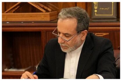 عباس عراقچی در حال نگاه کردن به تلفن همراه خود.