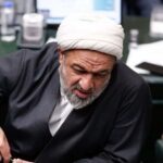 حمیدرضا رسایی در مجلس به جلو خم شده است.