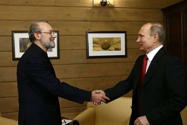 لاریجانی و پوتین با هم دست می‌دهند.
