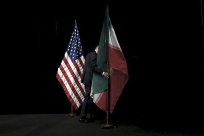 مذاکرات ایران و آمریکا. پرچم ایران توسط فردی از مقابل پرچم آمریکا برداشته می‌شود.